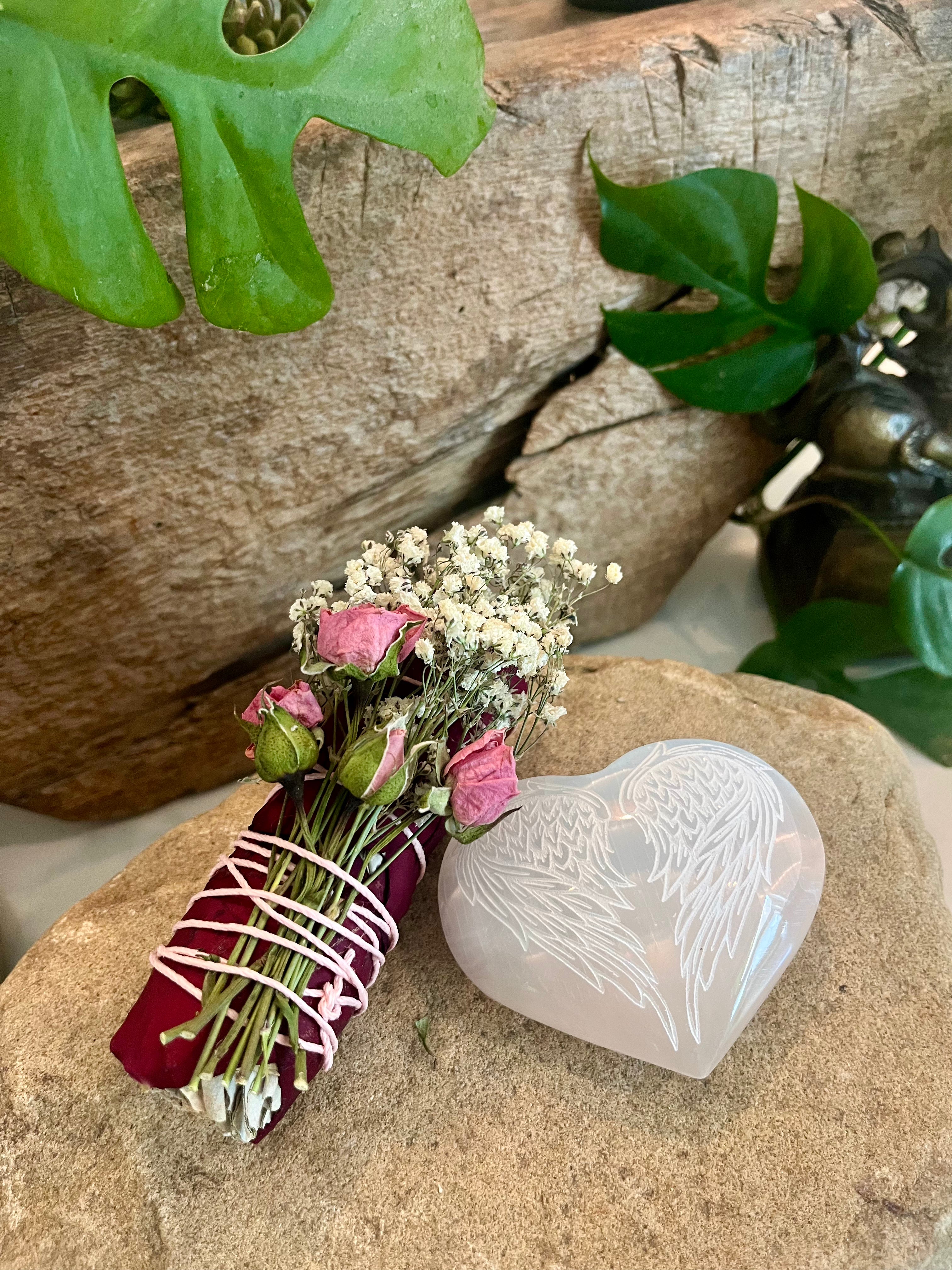 Rose Sage Baby's Breath 4" Smudge Bundle with 2" x 3" selenite heart-shaped crystal with engraved angel wings on top of healing stone