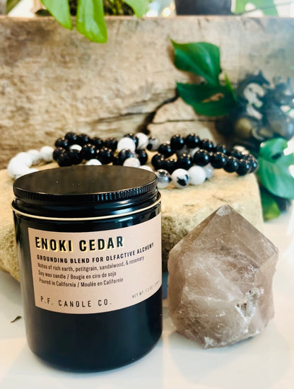 PF Candle Co. Enoki Cedar Scented Candle next to large Smoky Quartz Crystal point with 12 mm crystal bracelets (black obsidian, silver sheen obsidian, white howlite and rutilated quartz healing stones)
