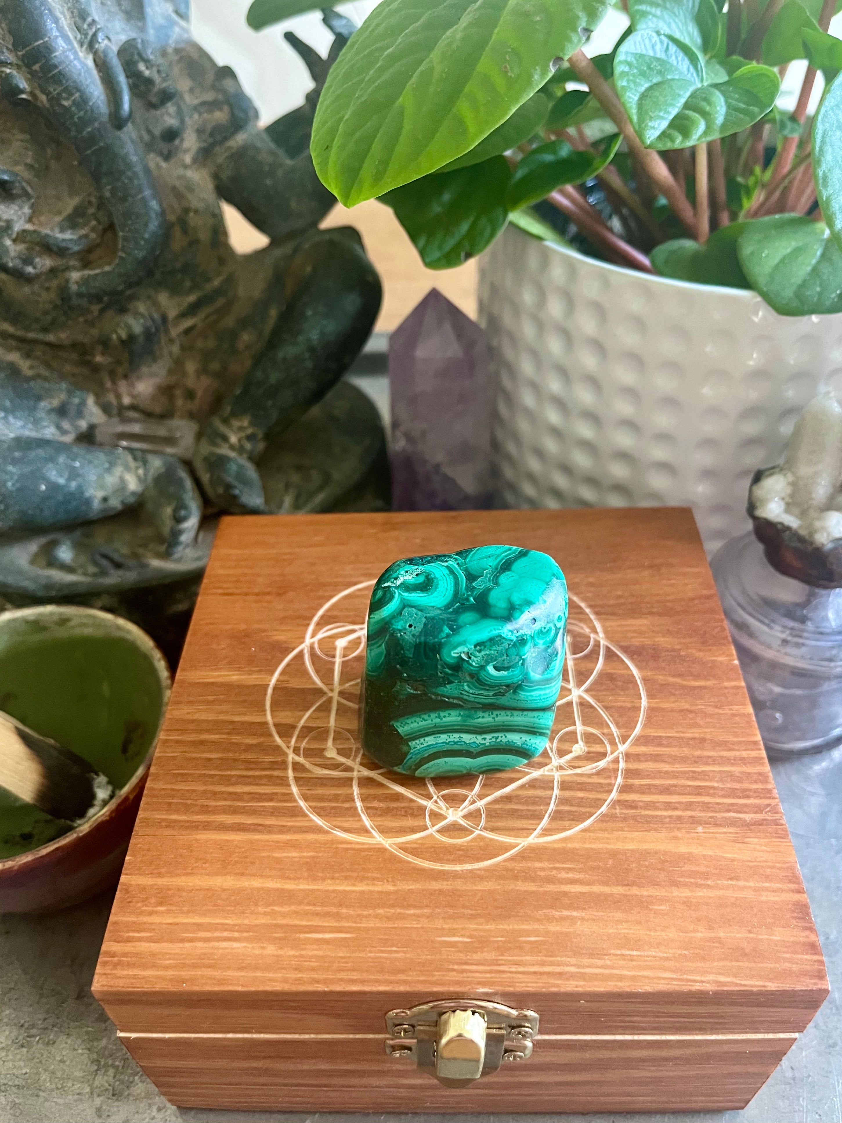 malachite crystal displayed on top of wooden box engraving of seed of life